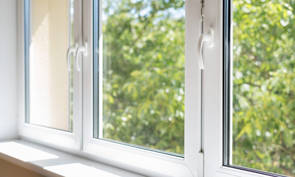 new plastic pvc window with white metal frame installed at modern house, view of blurred green trees. advertising concepts